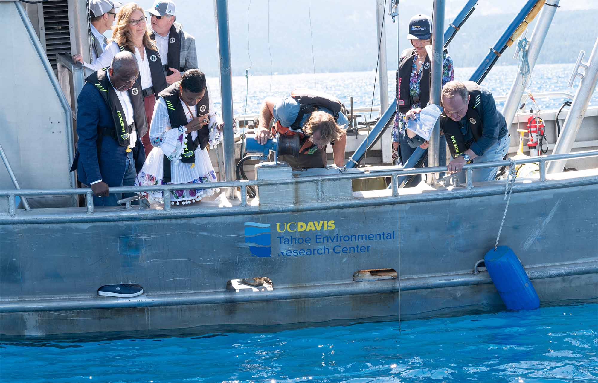 People peer over the edge of a boat into the water at Lake Tahoe