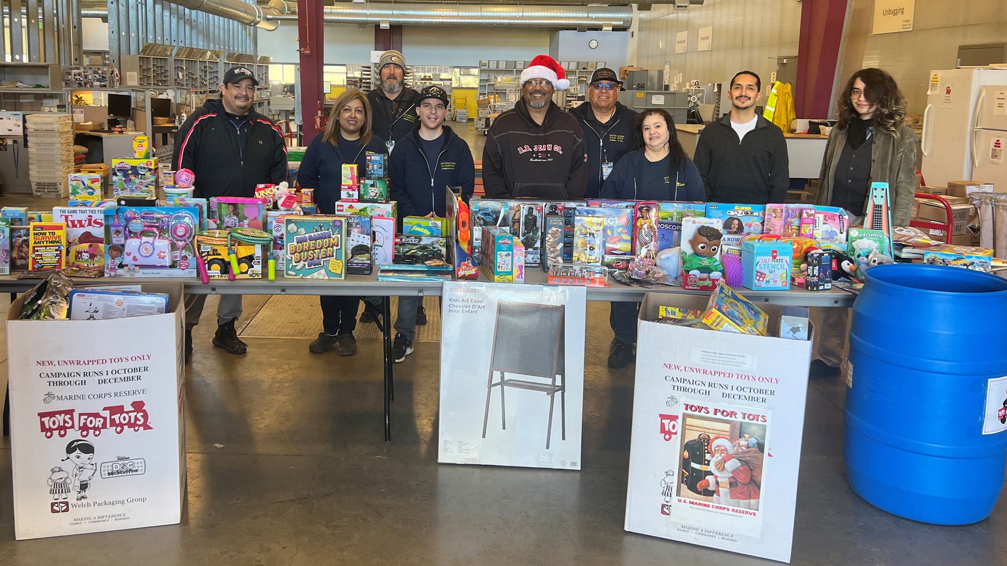 Men and women stand behind tables full of toys