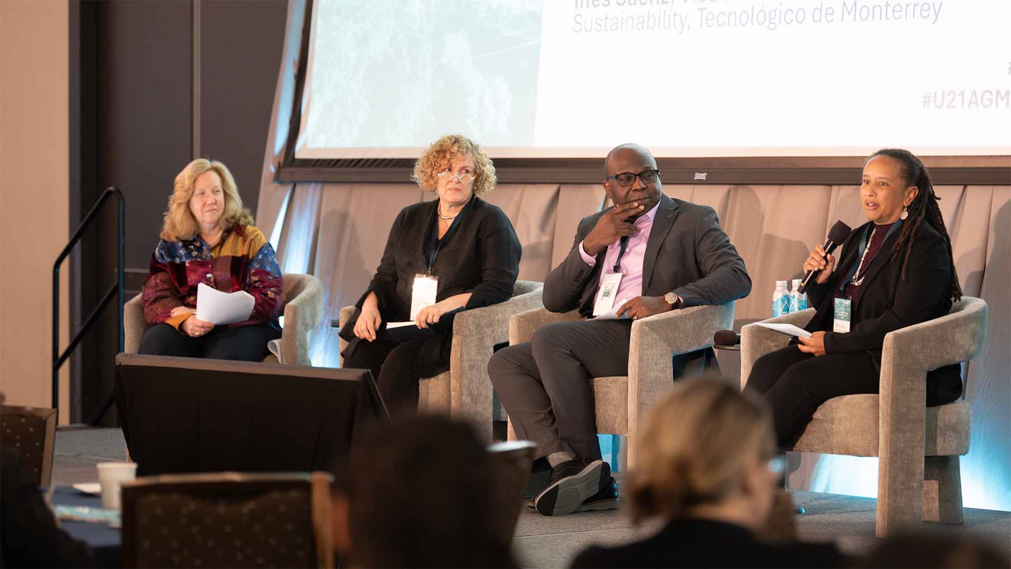 Four people sit on stage and speak to a crowd
