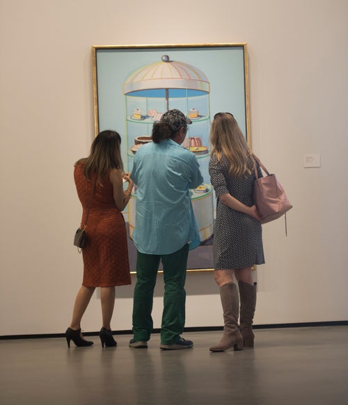  Three museum visitors gaze at a painting.