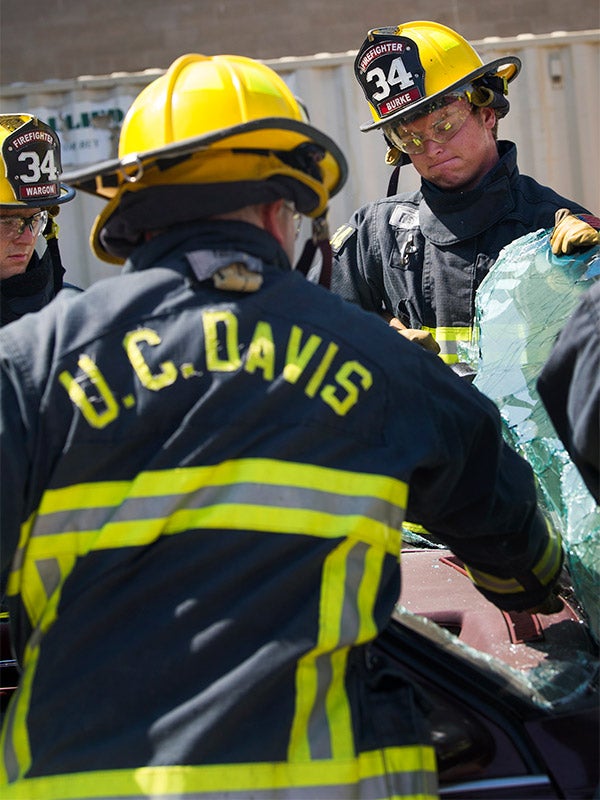 Student firefighter removes windshield from car.