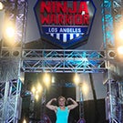 Anna Shumaker poses in front of American Ninja Warrior sign.