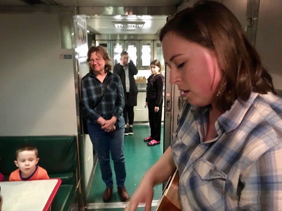 Woman plays ukelele on train.