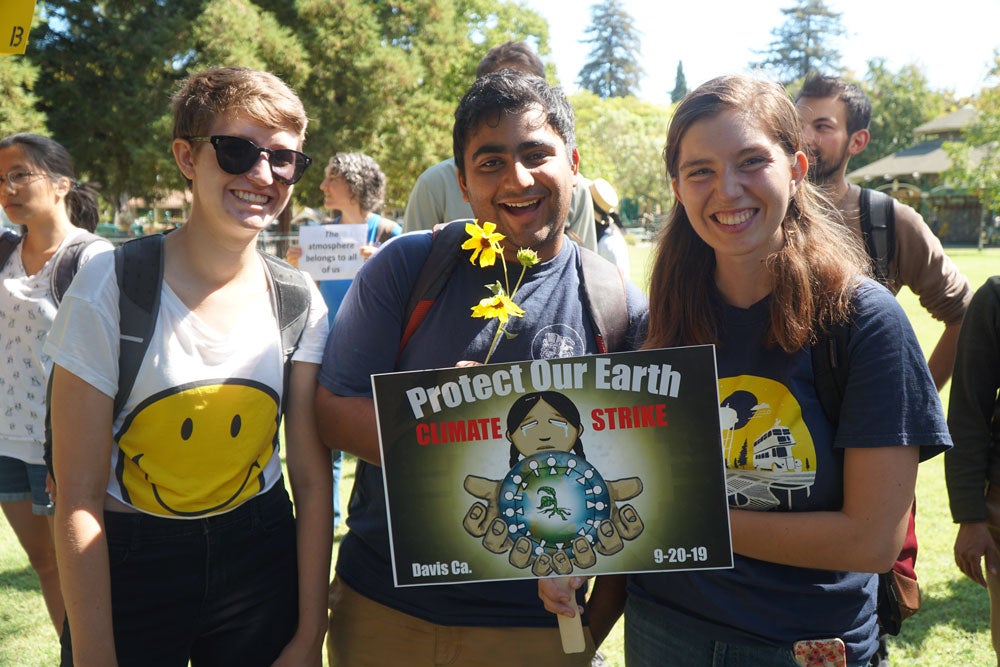 Climate strikers hold a sign and flowers.