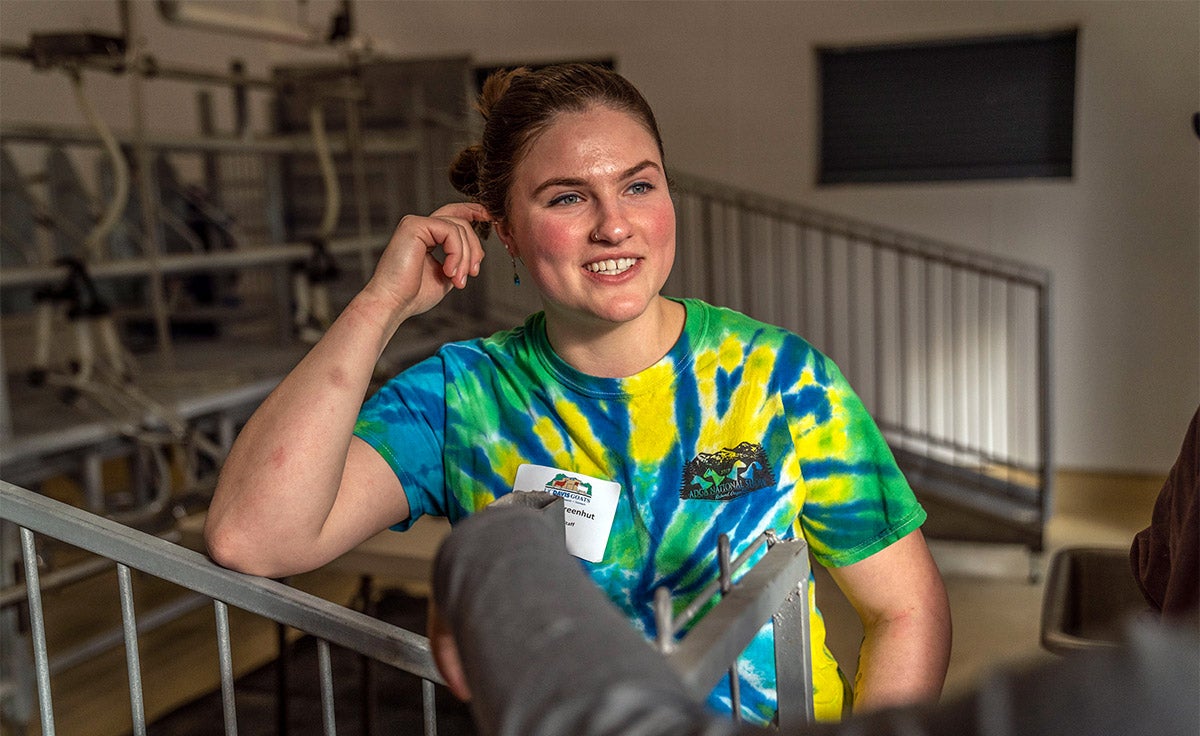Student stands in goat dairy.