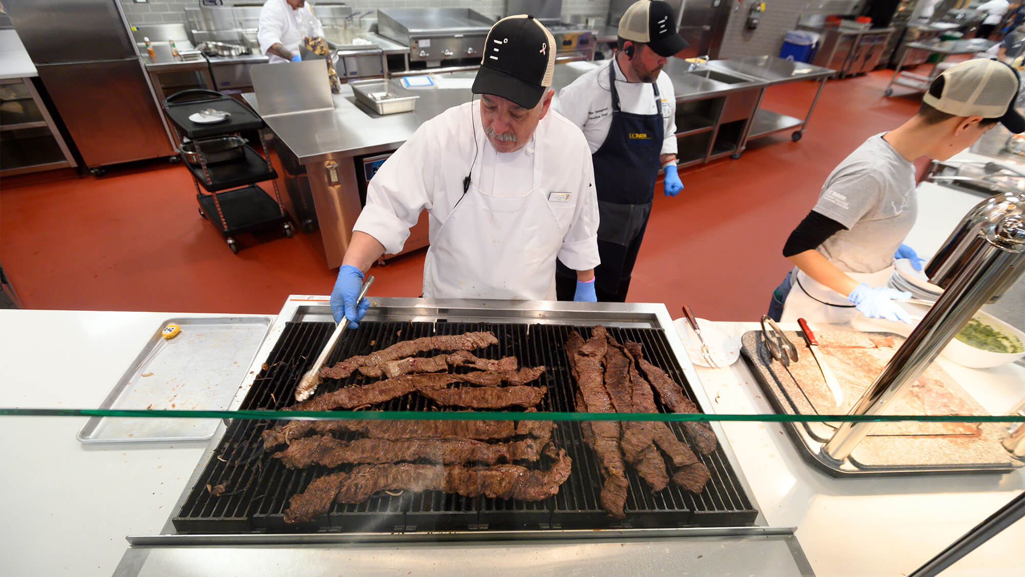 A chef cooks steak on a grill.