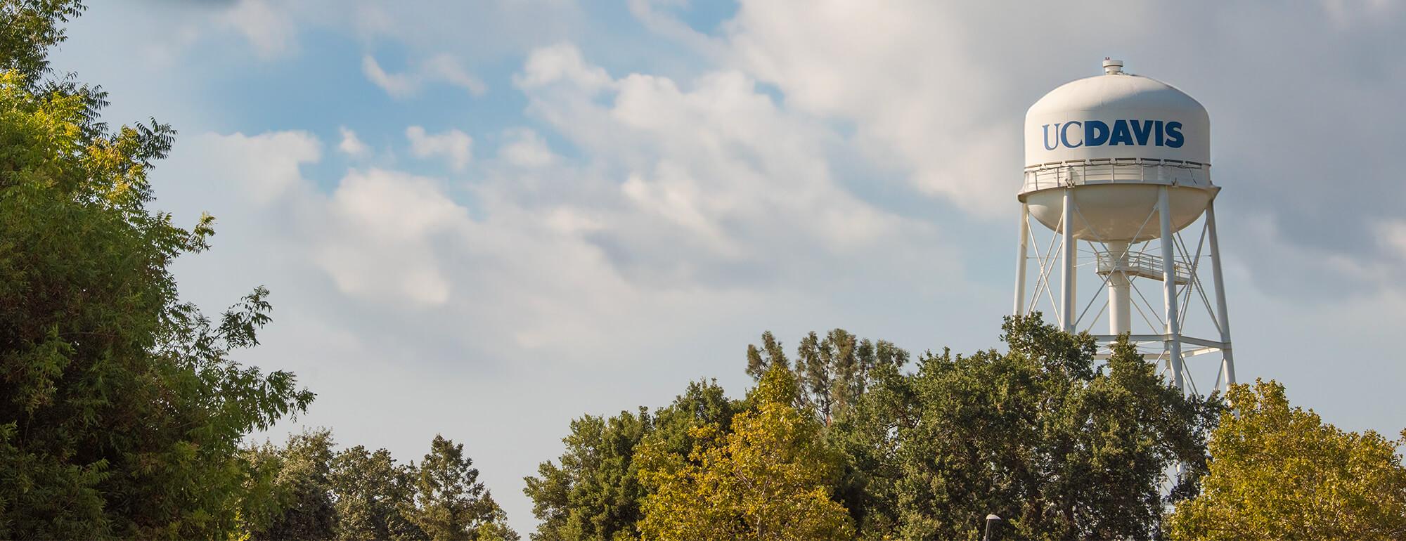 water tower above the tree line with clouds in the background