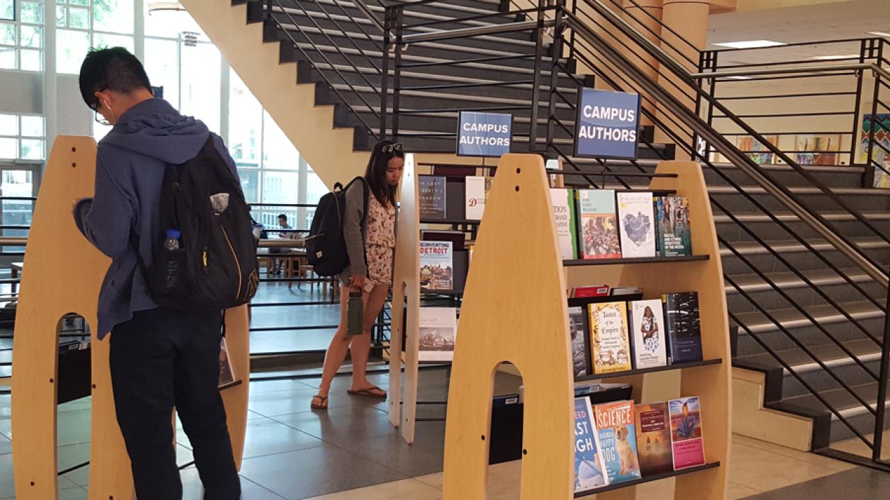 Library patrons peruse "Campus Authors" display.