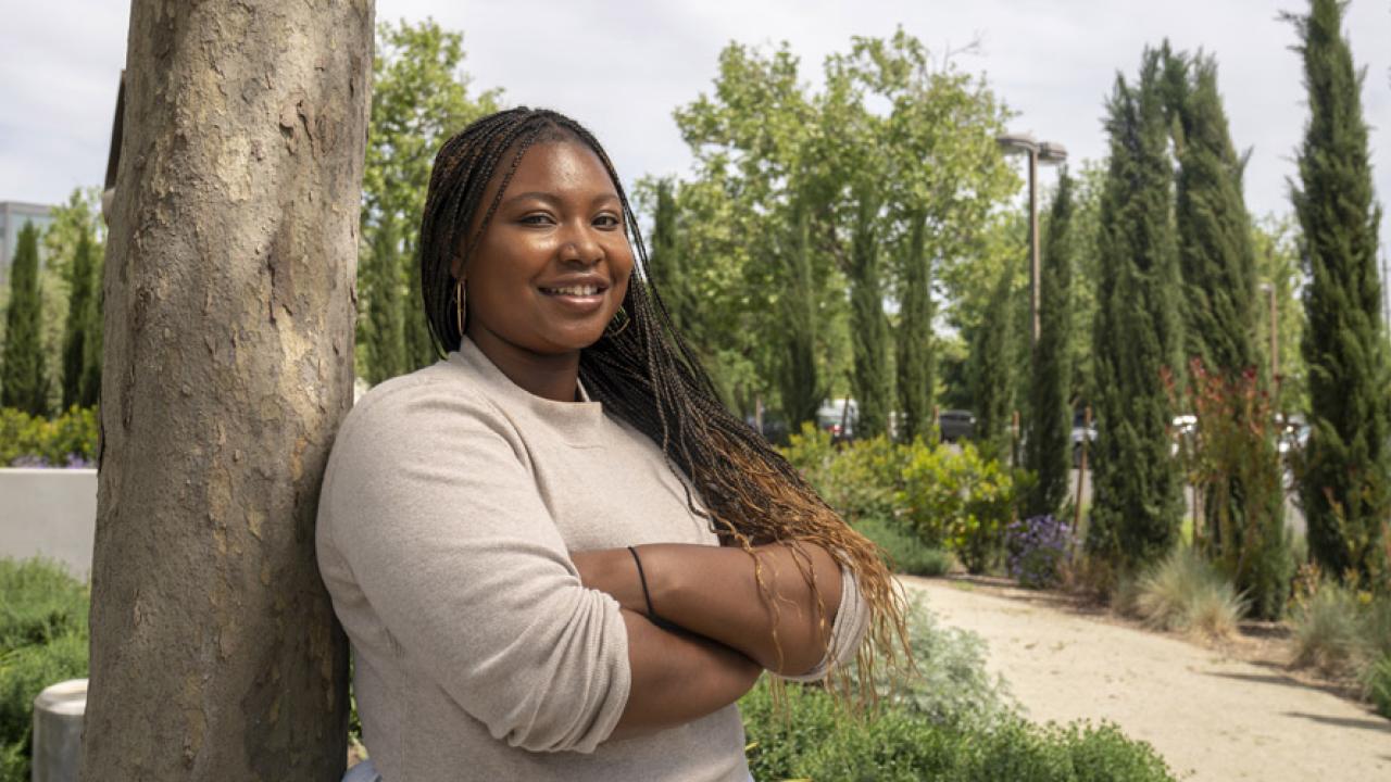 student leaning against a tree 