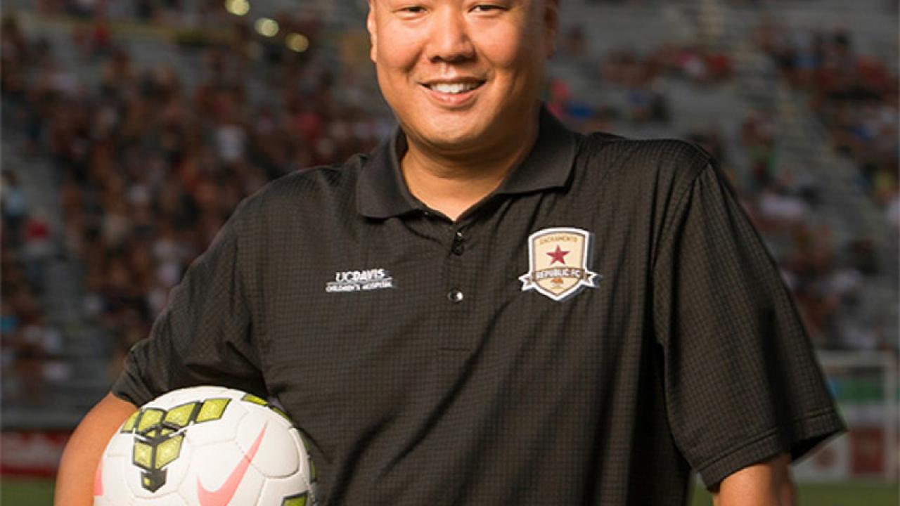 Political science graduate Brent Sasaki holding a soccer ball