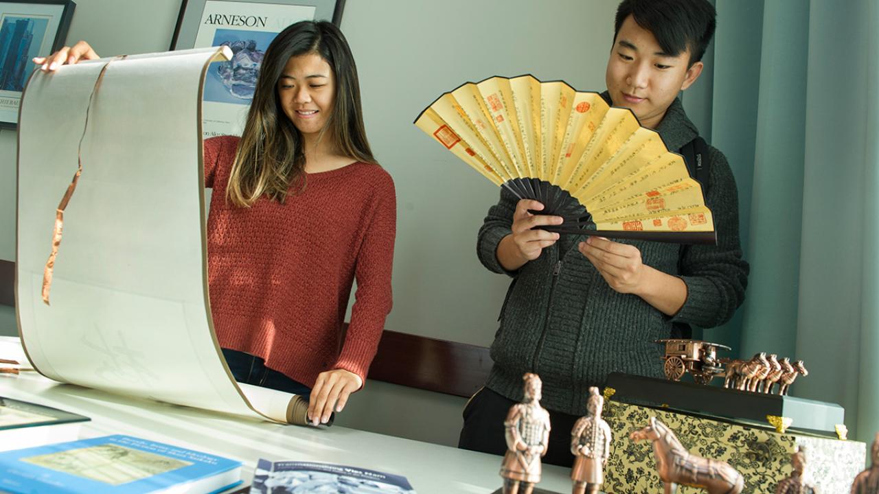 Senior communication major Karice Hui, left, and senior economics major Yongcong Cen view Asian art and cultural items