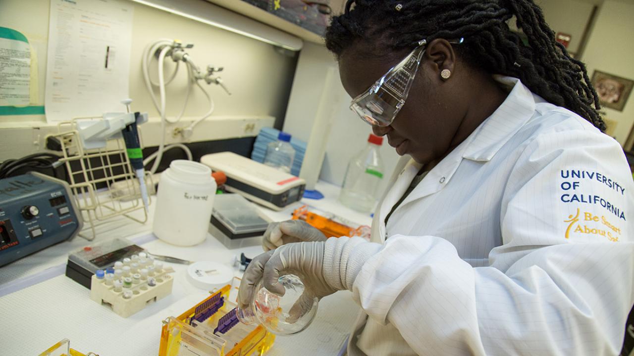 Female student in lab gear working on an experiment to separate DNA