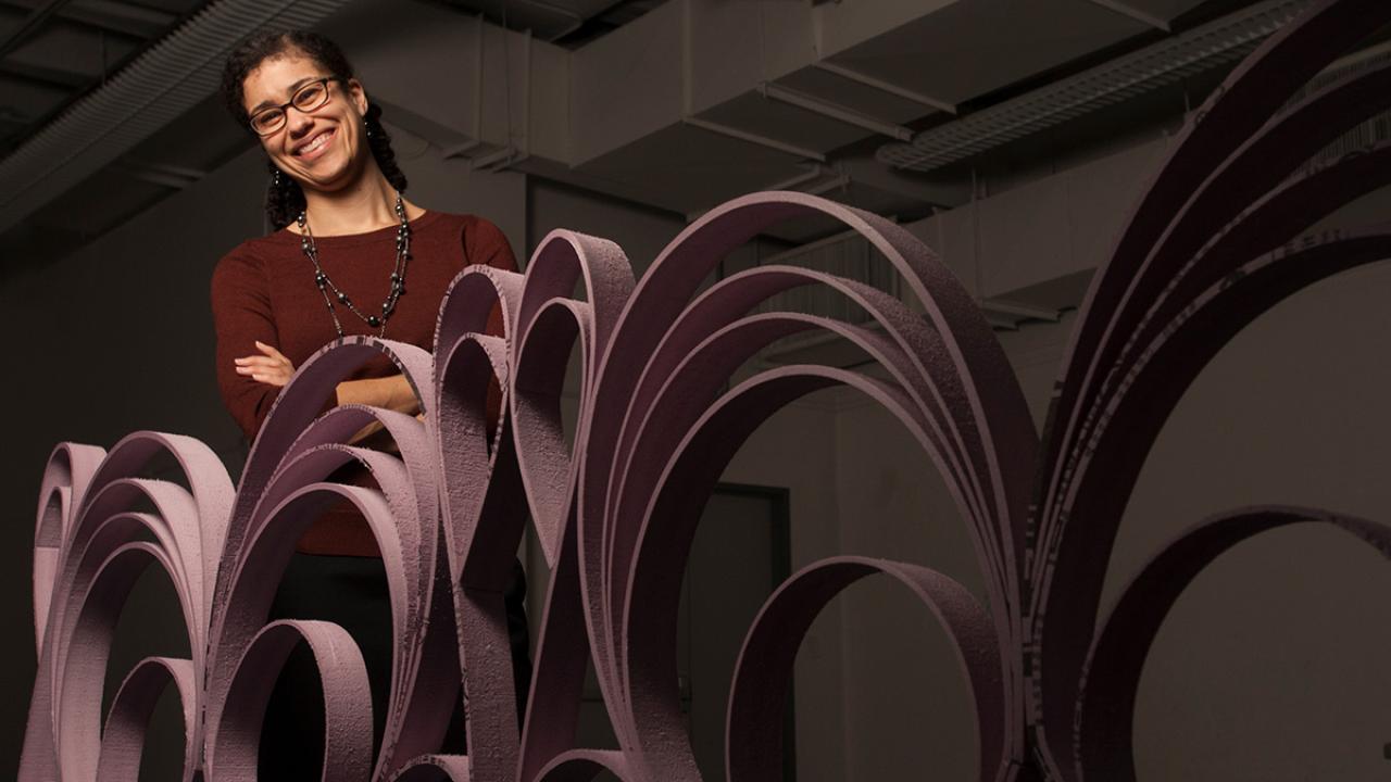 Academic advisor Ariel Collatz standing behind an artistic sculpture