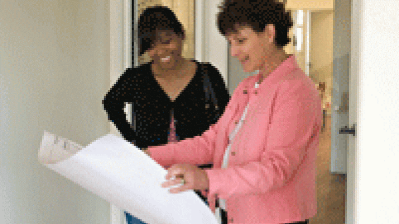 Cynthia  Picket, left, an associate professor of psychology and mother of a 2-year-old daughter, looks at planning documents for the center with regional manager Karen Valech.