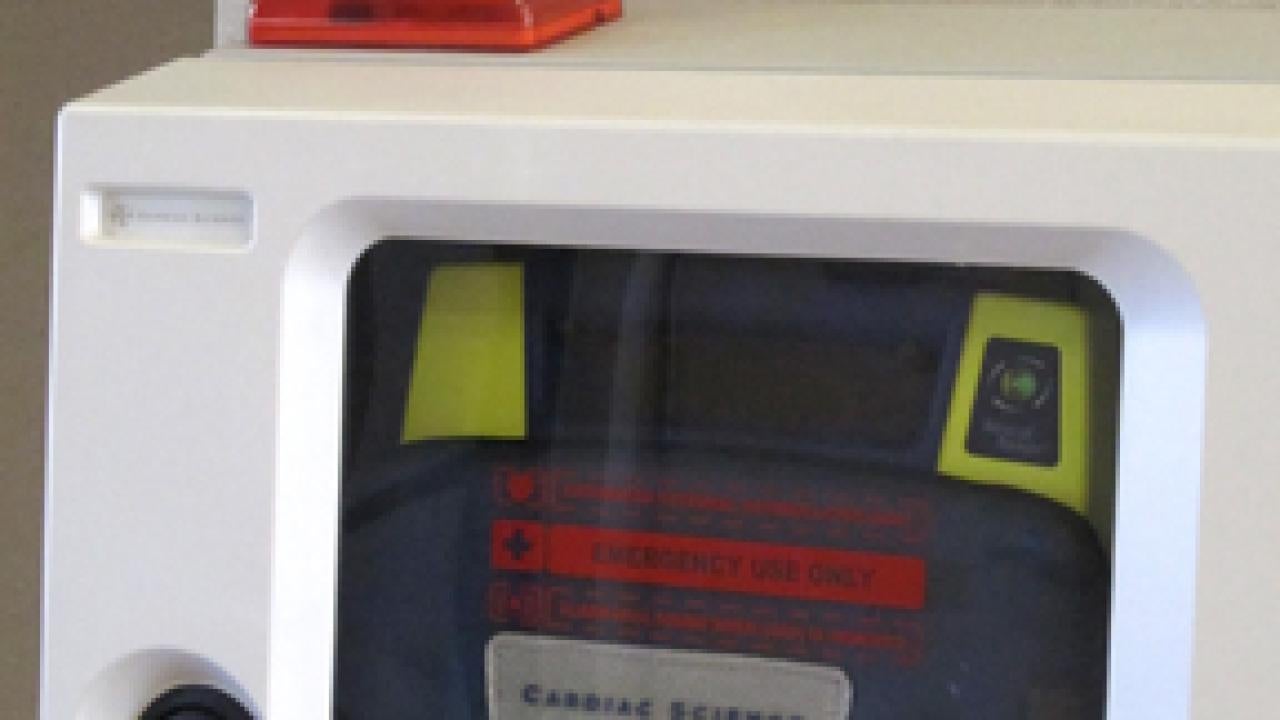 Photo: Automated external defibrillator and "AED" sign on a wall in the lobby of Mrak Hall