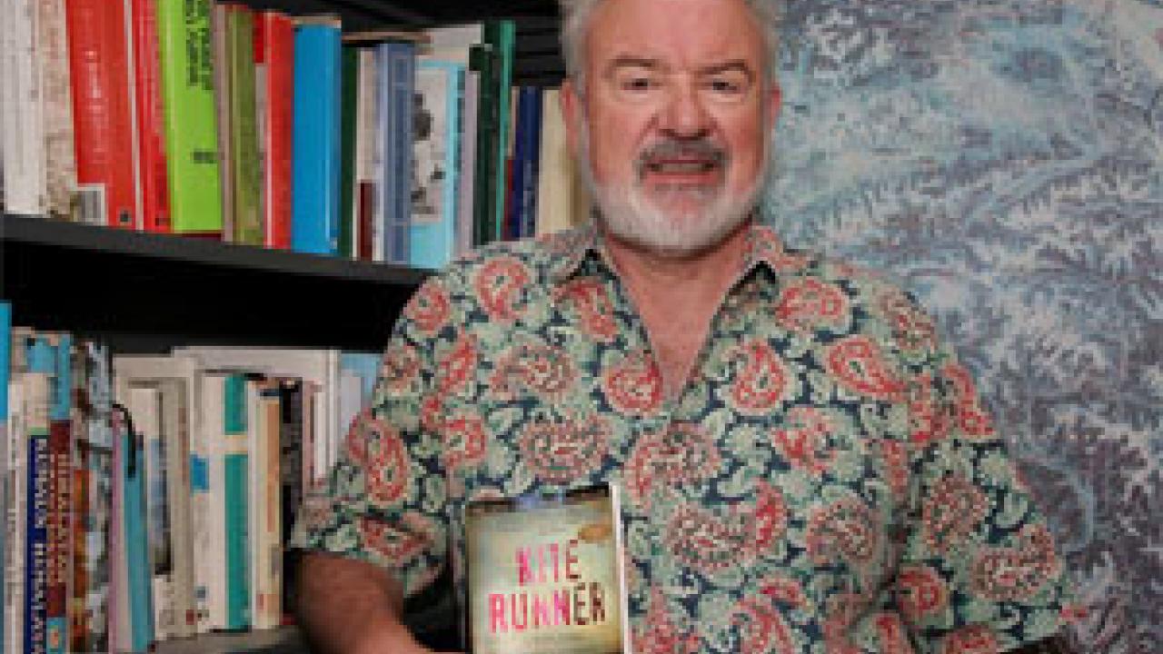 Nigel Allan is shown in his office, surrounded by textbooks and a topographical map of Afghanistan.