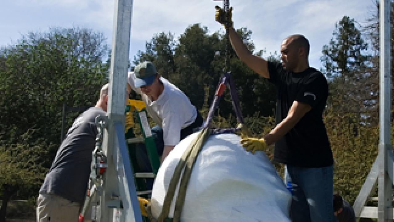 Workers from Ship Art International use a gantry to hoist one of the Eggheads.