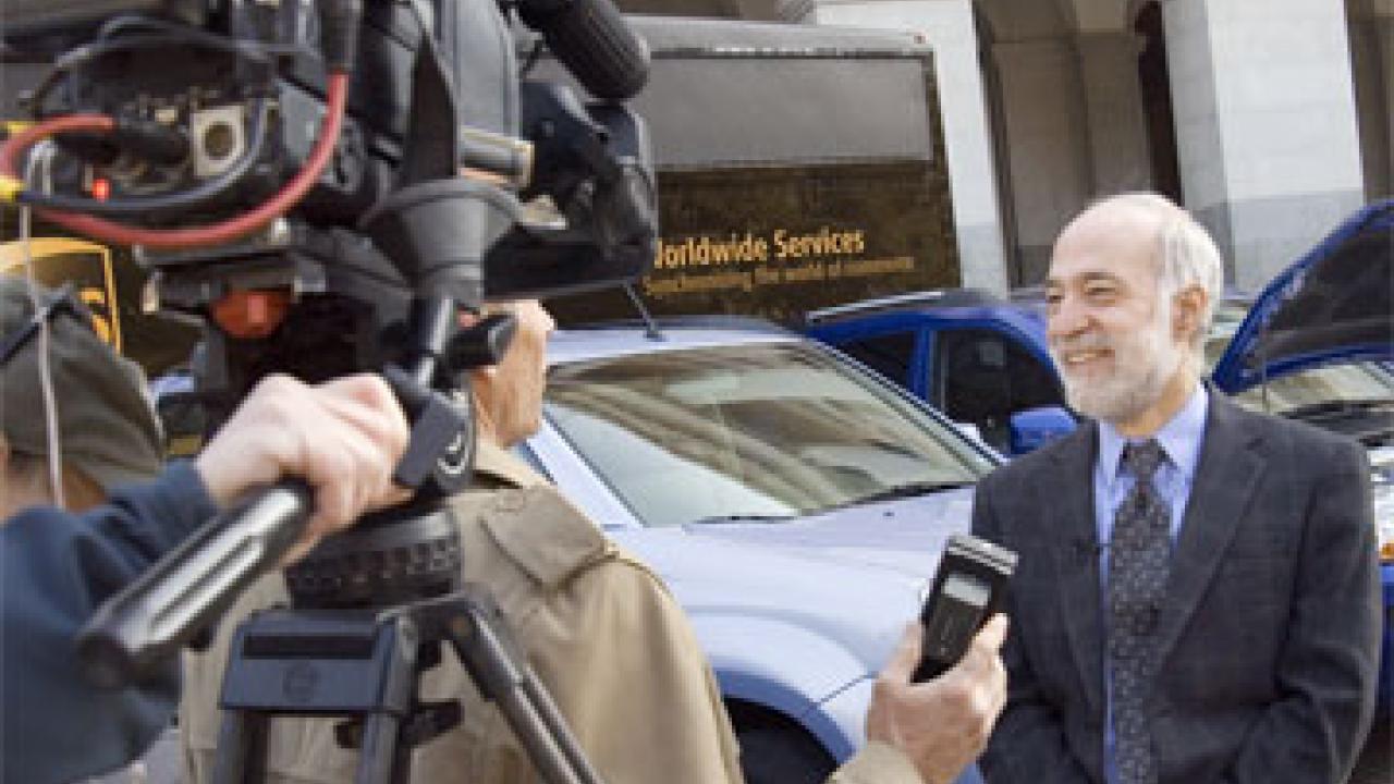 photo: man being interviewed by television reporter with camera behind