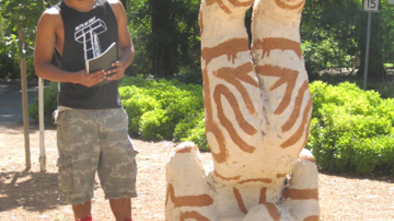 Photo: Bryan Ramirez-Corona views his untitled "green" sculpture in the outdoor exhibition.