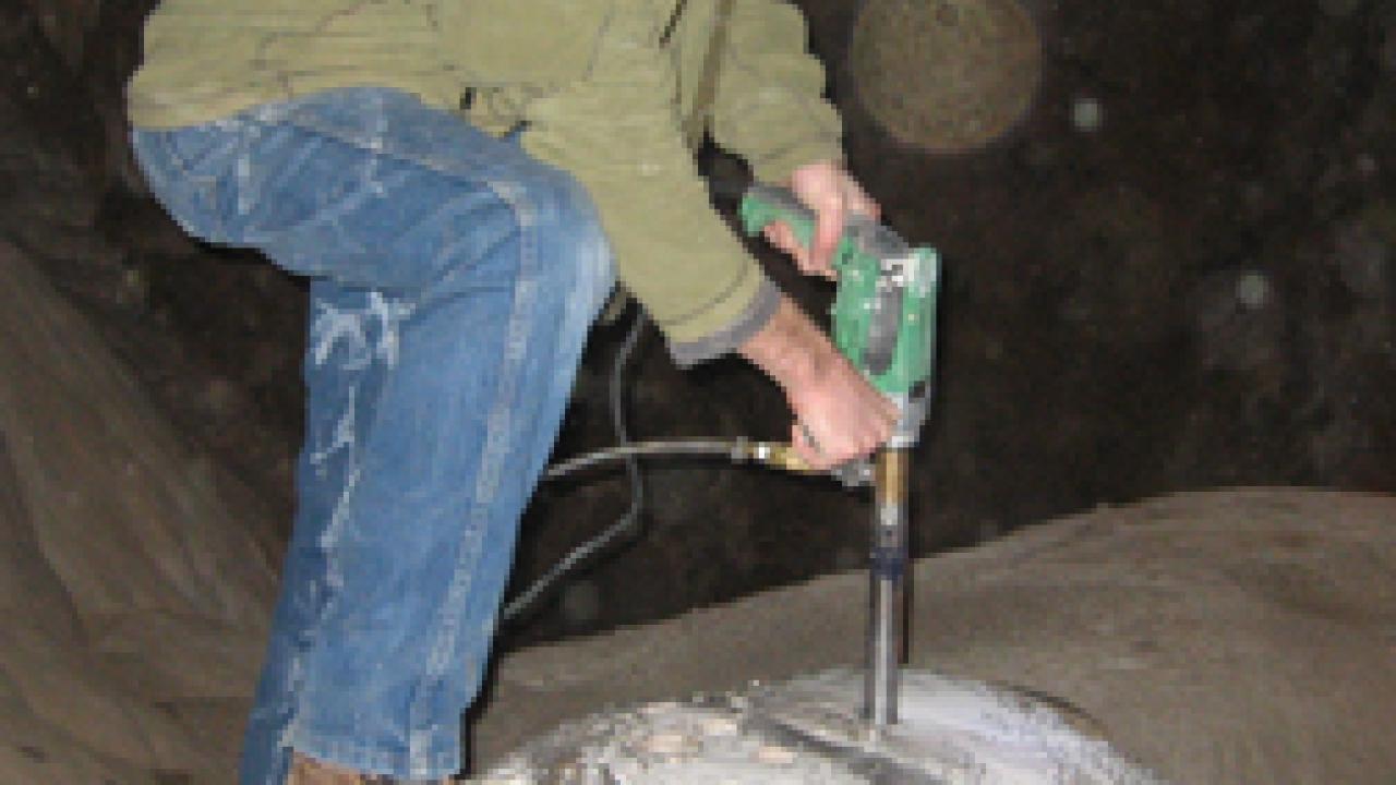 Neil Kelley, a doctoral student in geology, drills into a stalagmite at Moaning Cavern.