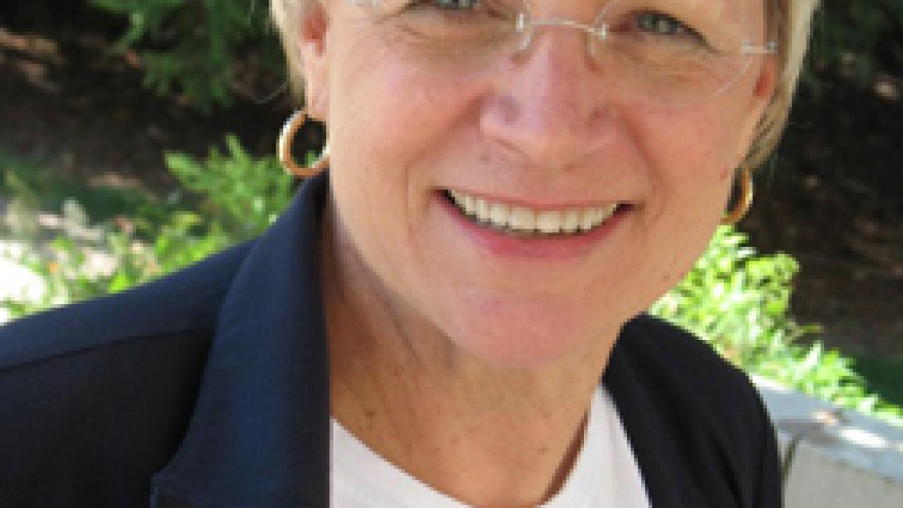 Laurie Lewis displays the centennial lapel pin with the 100-year logo that she designed.