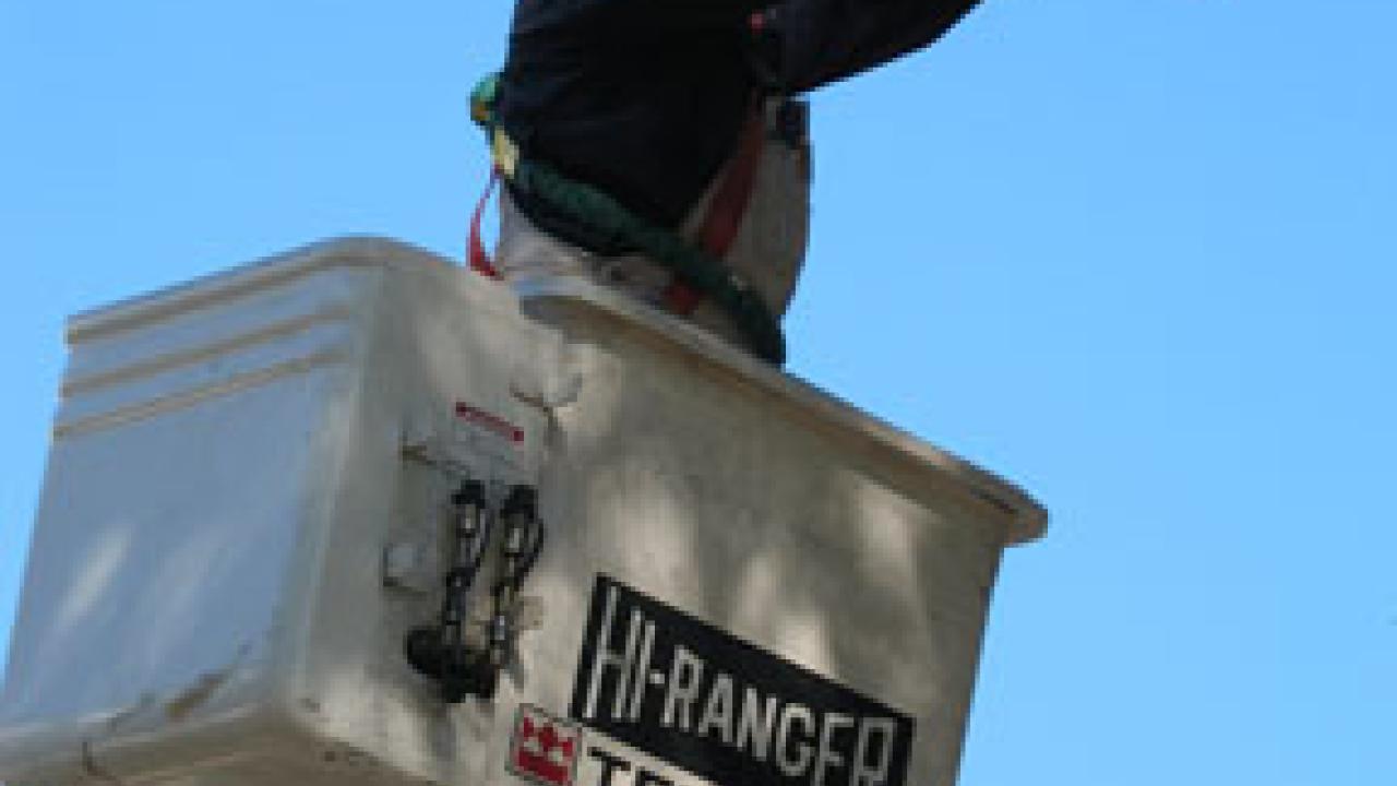 After putting a new lamp in a streetlight on Hutchison Drive, campus electrician Rick Noring works on repairing the fixture -- which he ends up replac