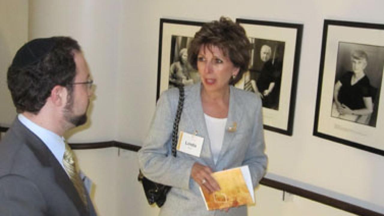 Photo: Chancellor Linda P.B. Katehi chats with Mark Katrikh of the Museum of Tolerance against a backdrop of photos of Holocaust survivors.