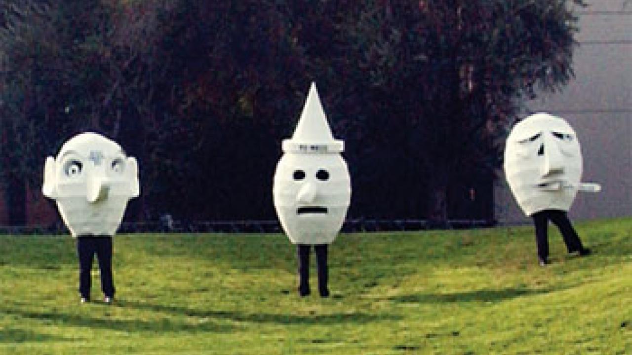 photo: three people inside giant human heads