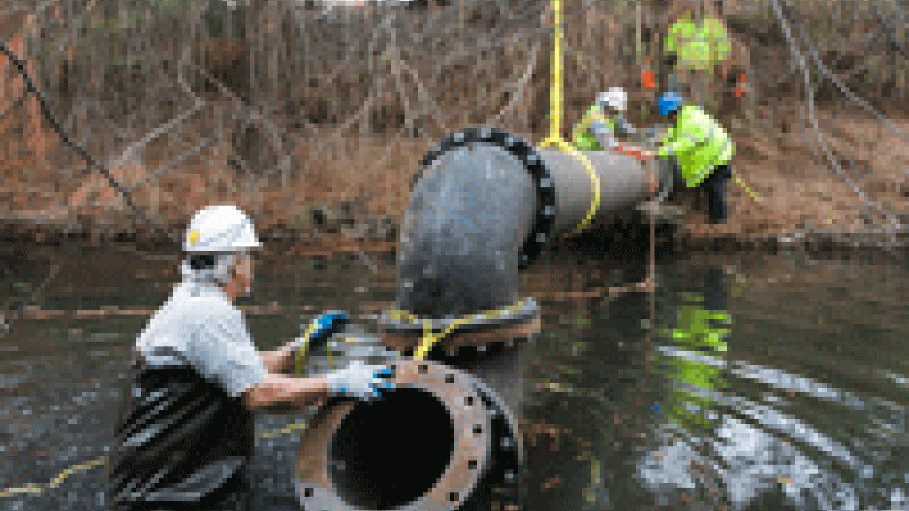 Utility Services workers installed the inlet pipe for the waterway improvement project late last year. Water foreman Mel Garcia is in the foreground. Pictured on either side of the pipe are Dwayne Straub, senior building maintenance worker, left