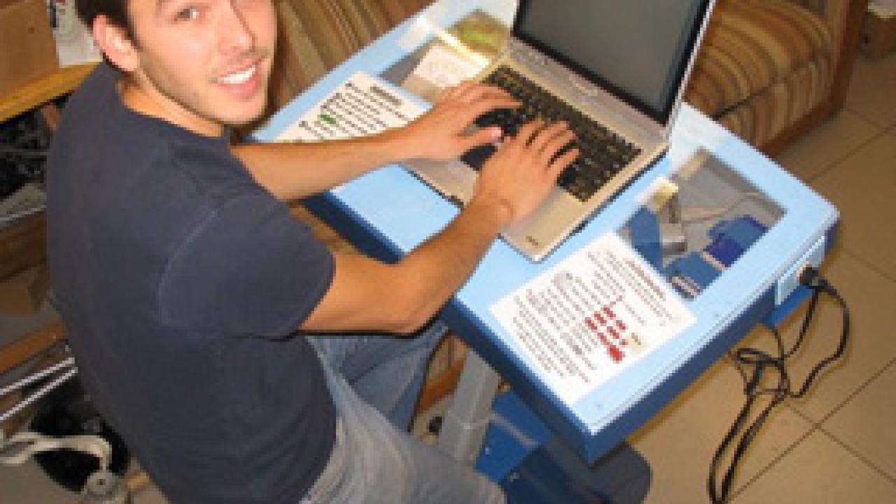 Graduate student Tai Stillwater is pictured on the Pedal Powered Charging Table, a project that he worked on.