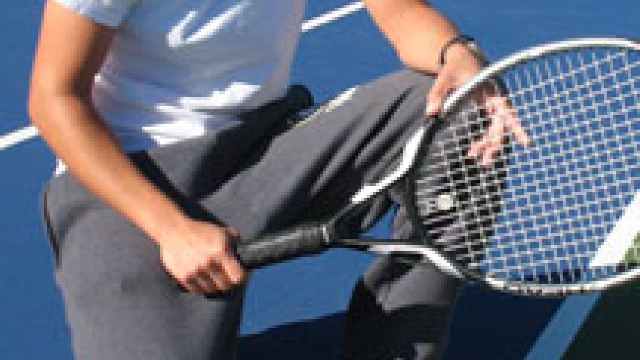 Sara Morenc '01, assistant coach for the Aggie women's tennis team, shows a ball that is in -- because at least part of the ball is touching the line.