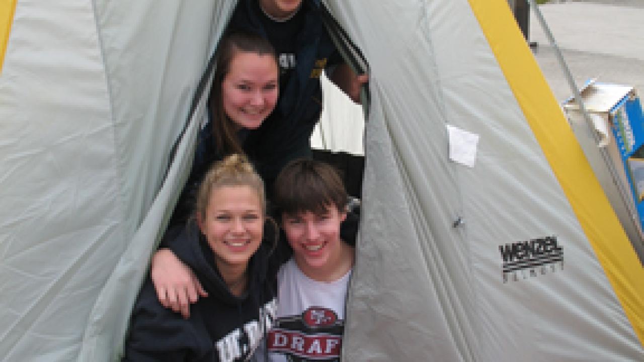 Students Chris Perry, Courtney King, Jamie Flynn and Adam Darbonne peek out of a tent outside the Pavilion.