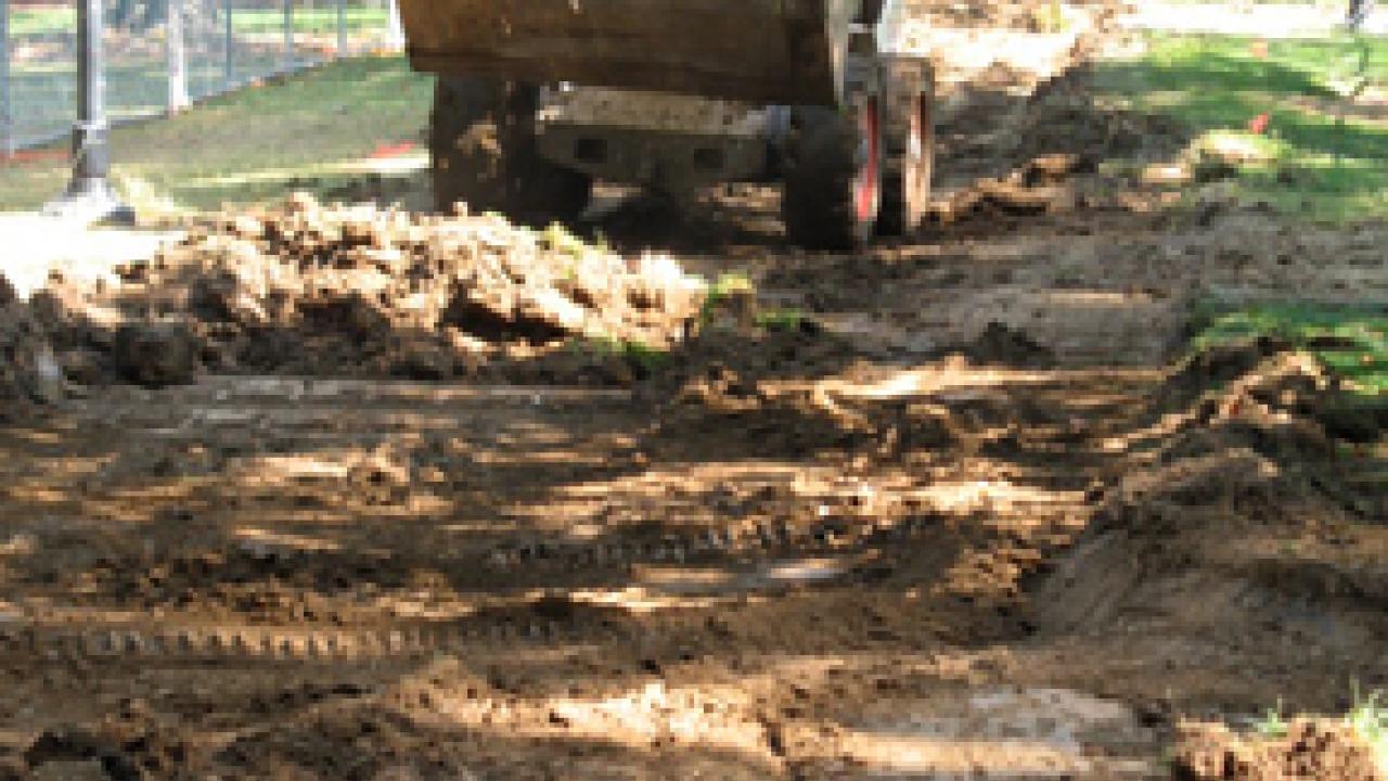 Equipment operator excavates the historic path where a concrete walkway has been removed to make way for the new Centennial Walk.