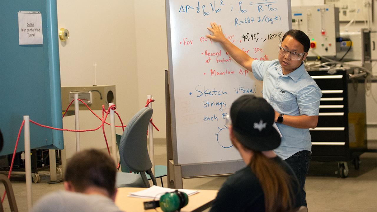 Student standing in front of white board full of engineering calculations.