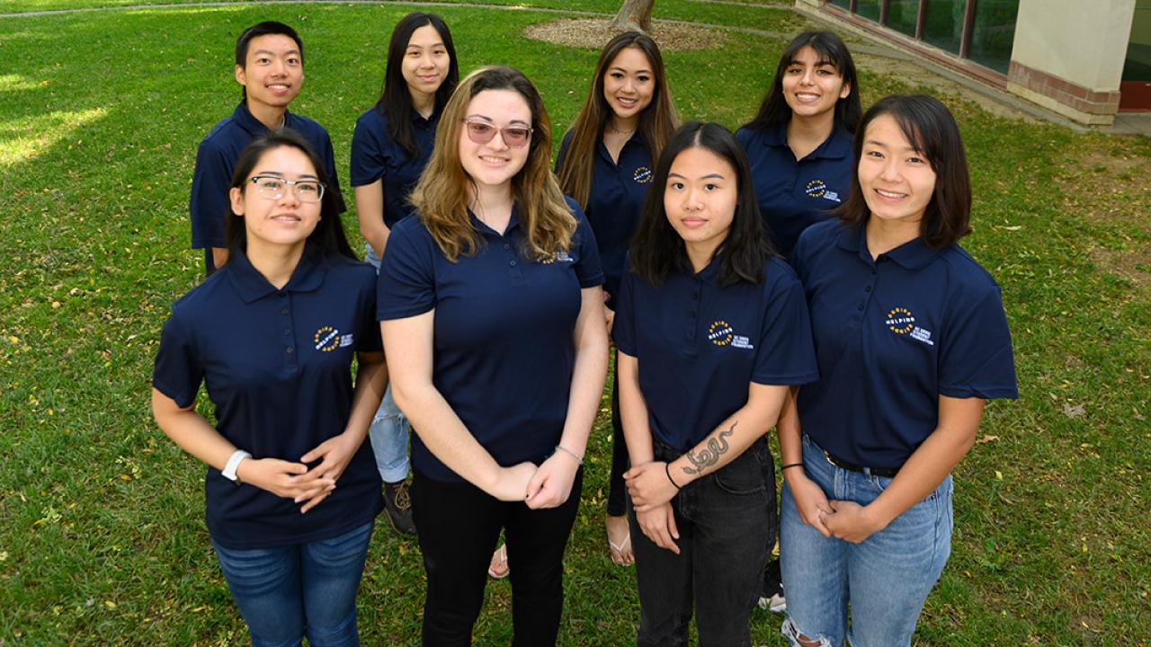 Photo of eight students wearing Aggies Helping Aggies polo shirts.