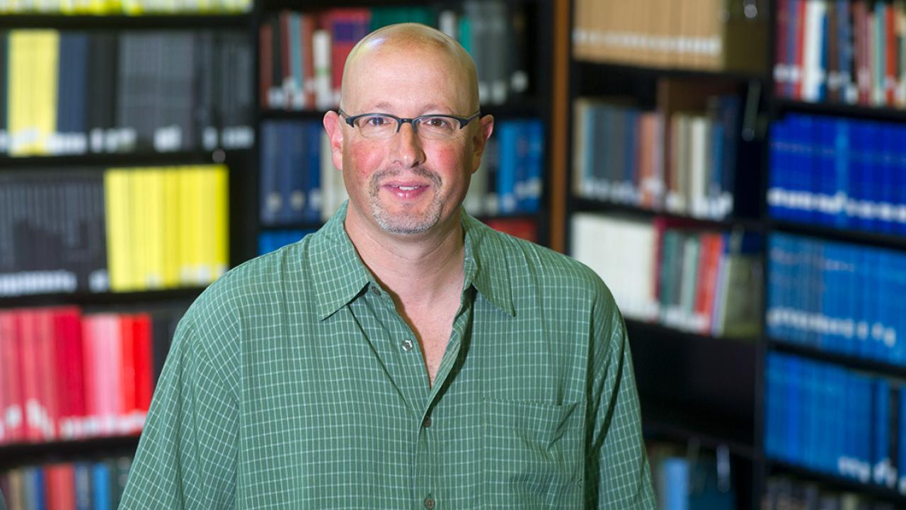 Ari Kelman stands in front of books.