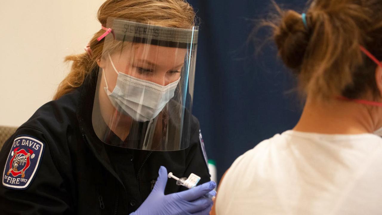 Student EMT in uniform gives shot.