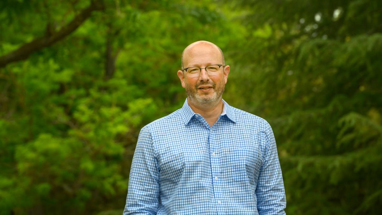 Ari Kelman, agianst backdrop of campus greenery