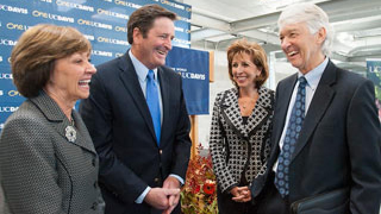 Four people smiling and conversing while standing 