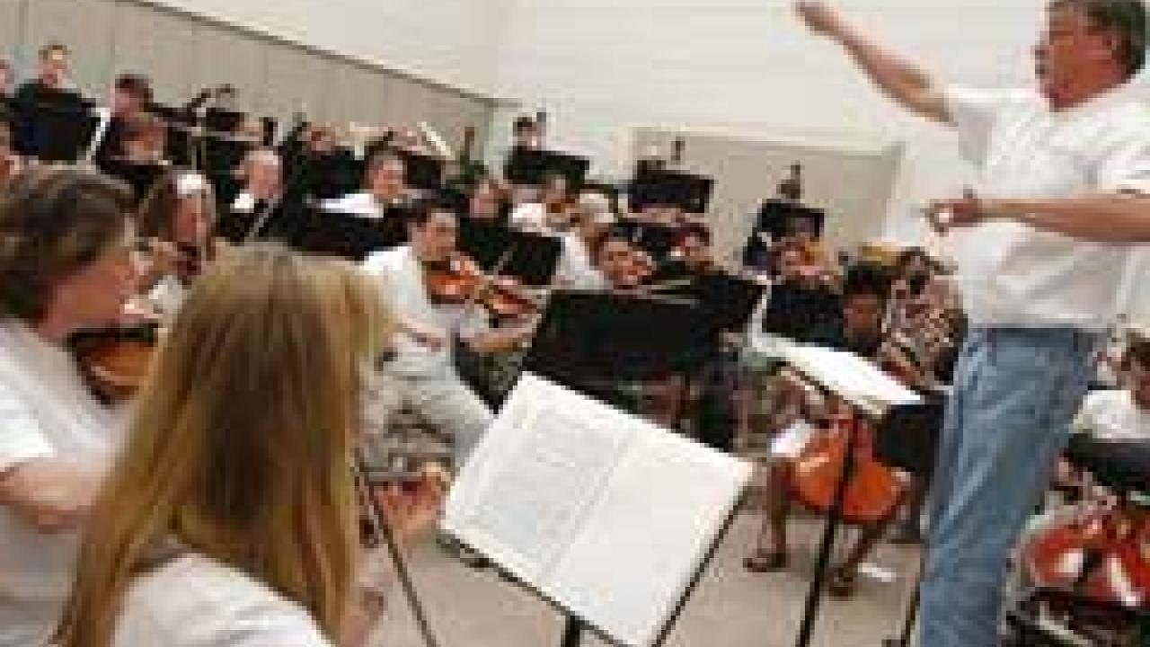 photo of conductor on stand and symphony playing