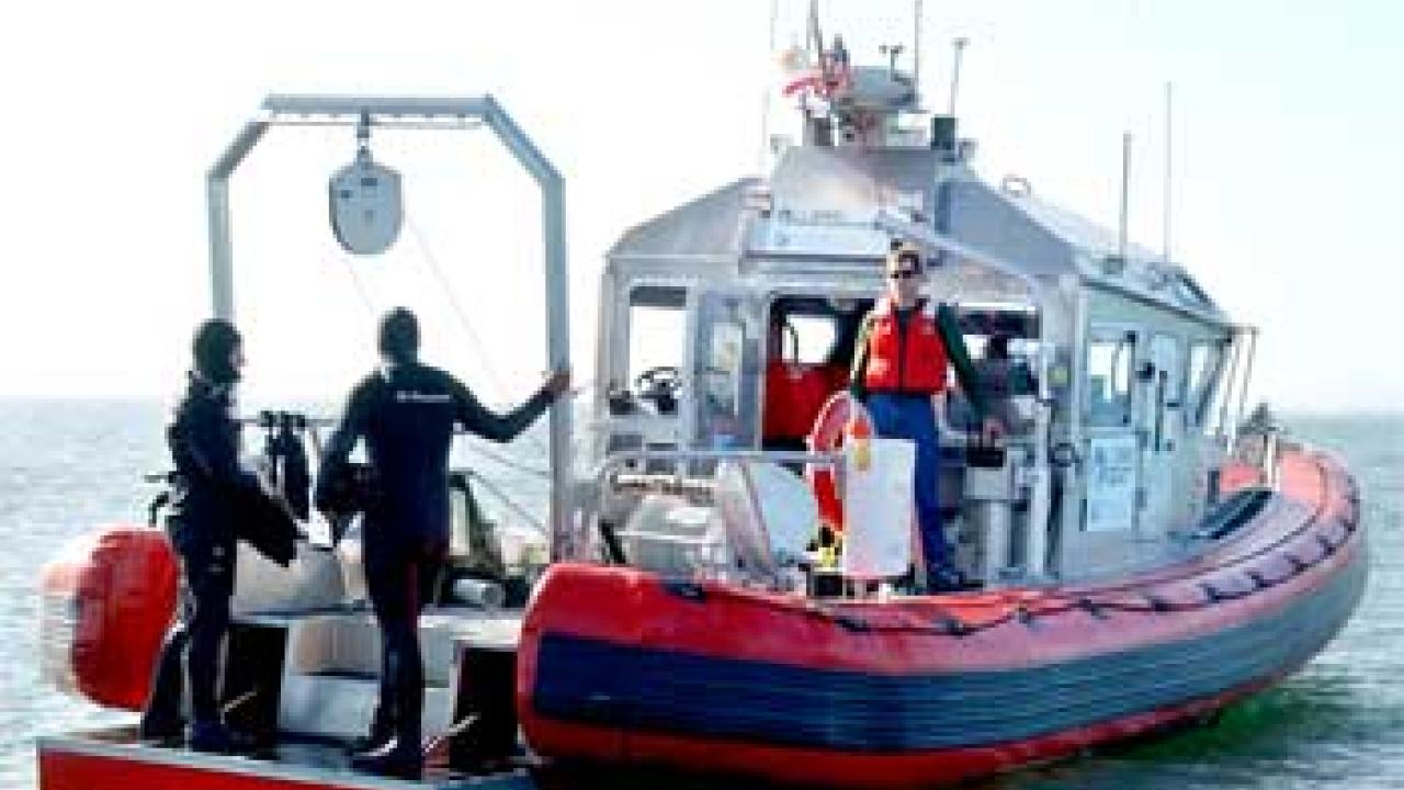 Photo: two divers standing at the end of a boat on the ocean