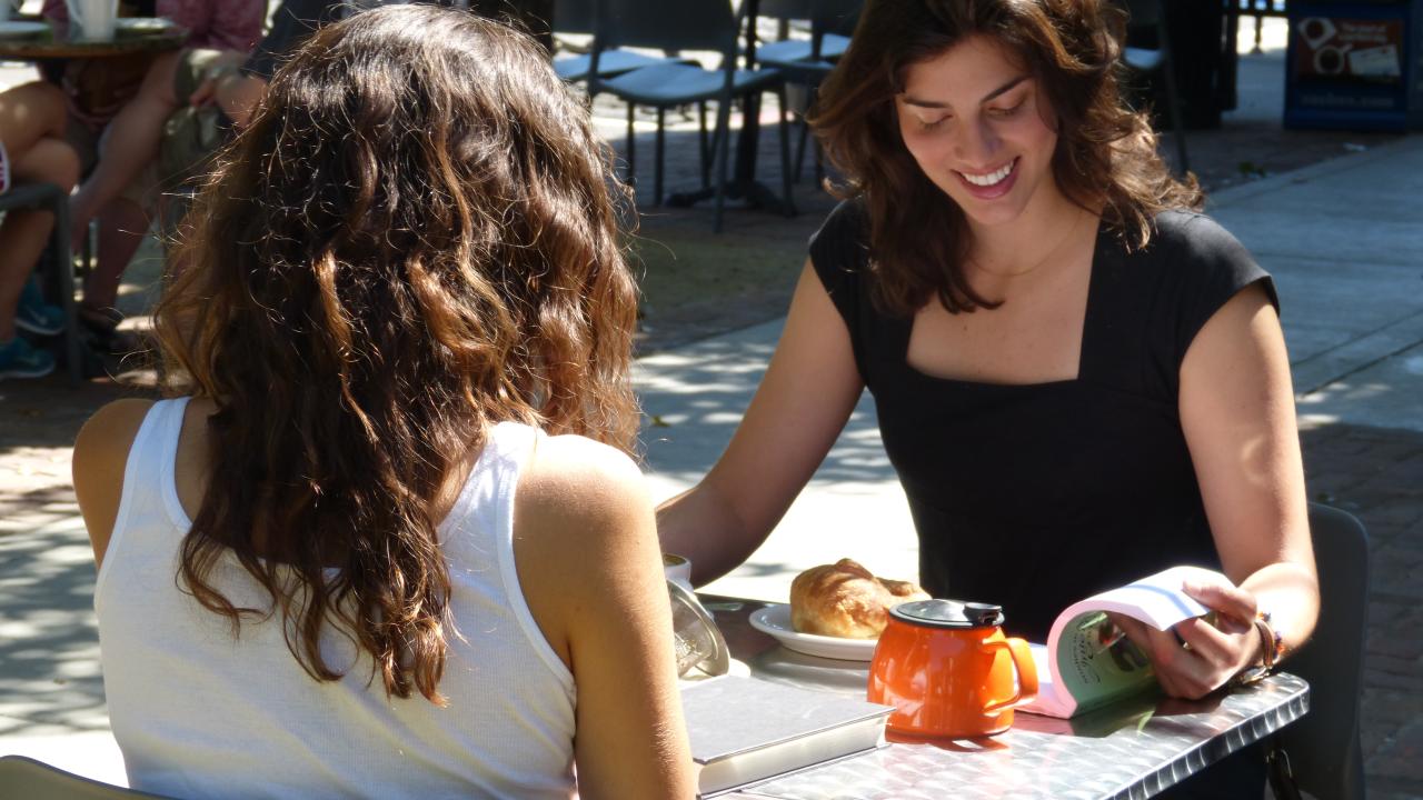 Two women read while seated at table