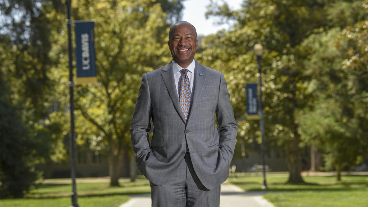Chancellor Gary S. May, standing, smiling, portrait on Quad.