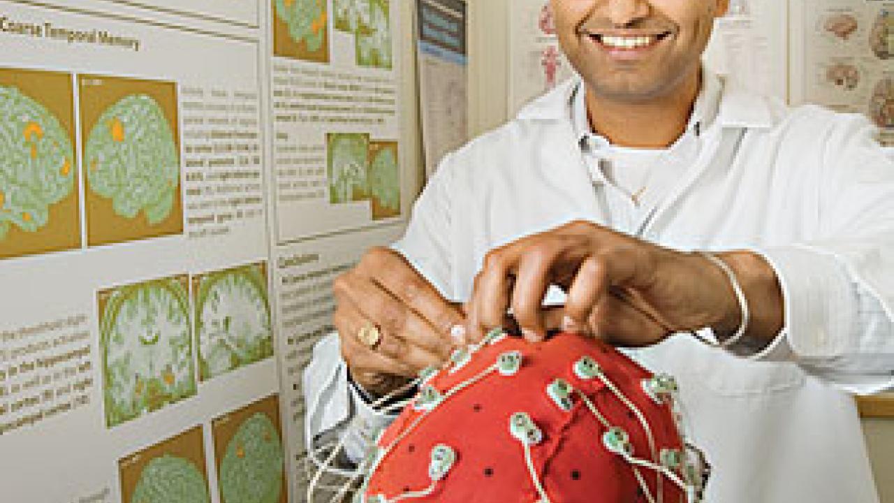 Charan Ranganath, in a lab coat, adjusting wires on a research subject.