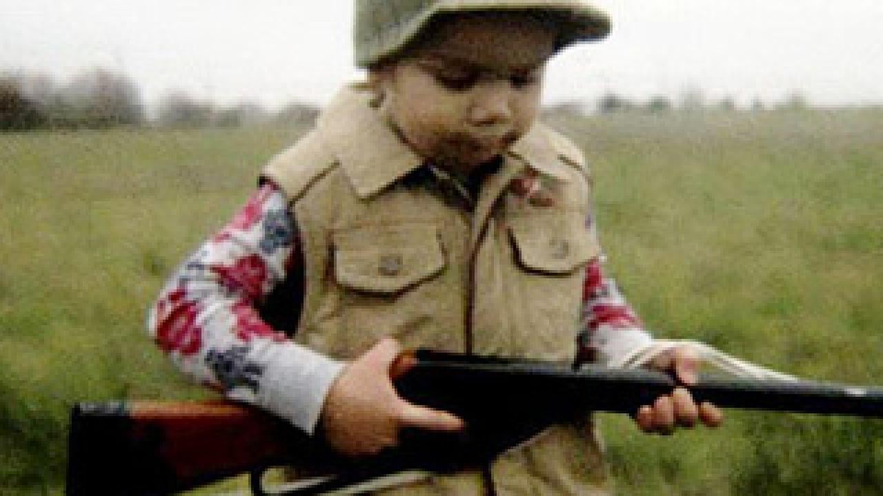 Photo: little boy in a cap holding a rifle