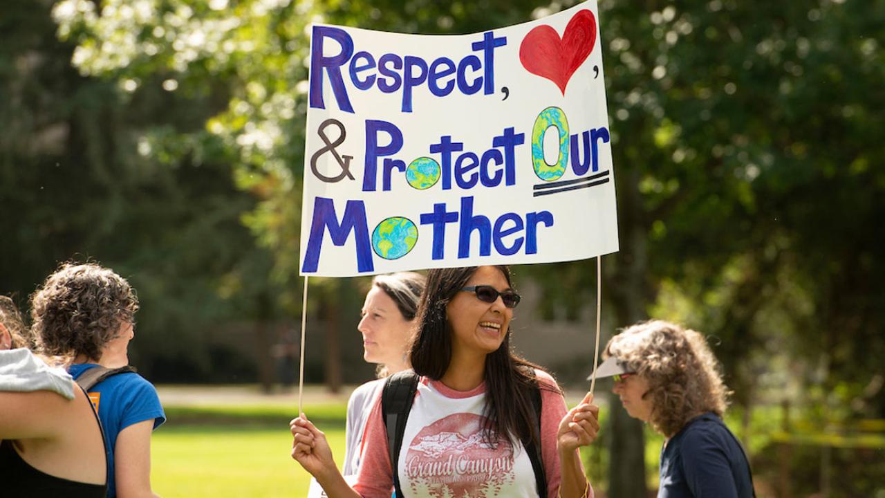 Woman at Climate Action Strike, holding sign encouraging people to respect, love and protect our Mother Earth