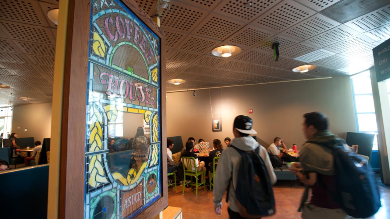 Two people walk by stained-glass Coffee House sign