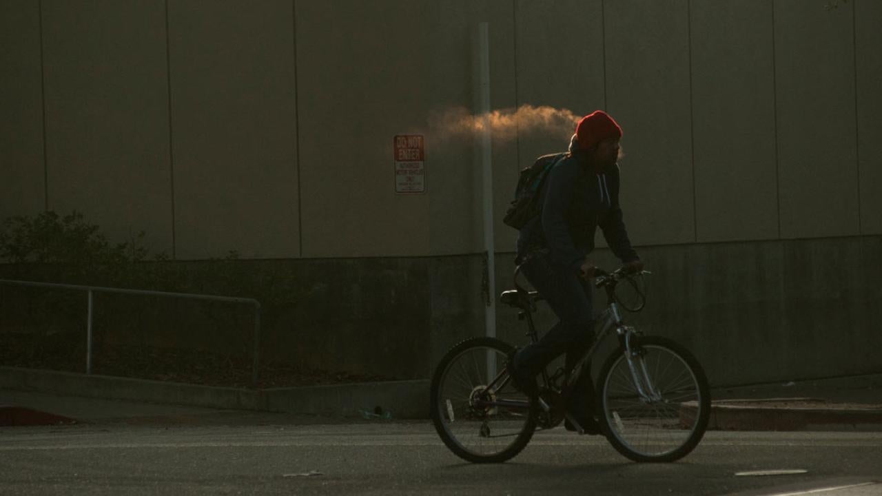 Bicyclist's breath condenses into what looks like a cloud or fog.