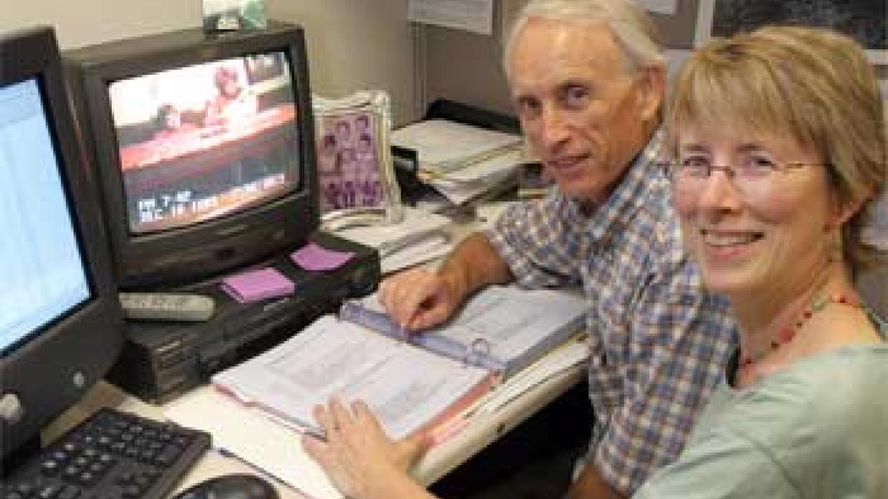 Photo: man and woman in front of computer looking at camera