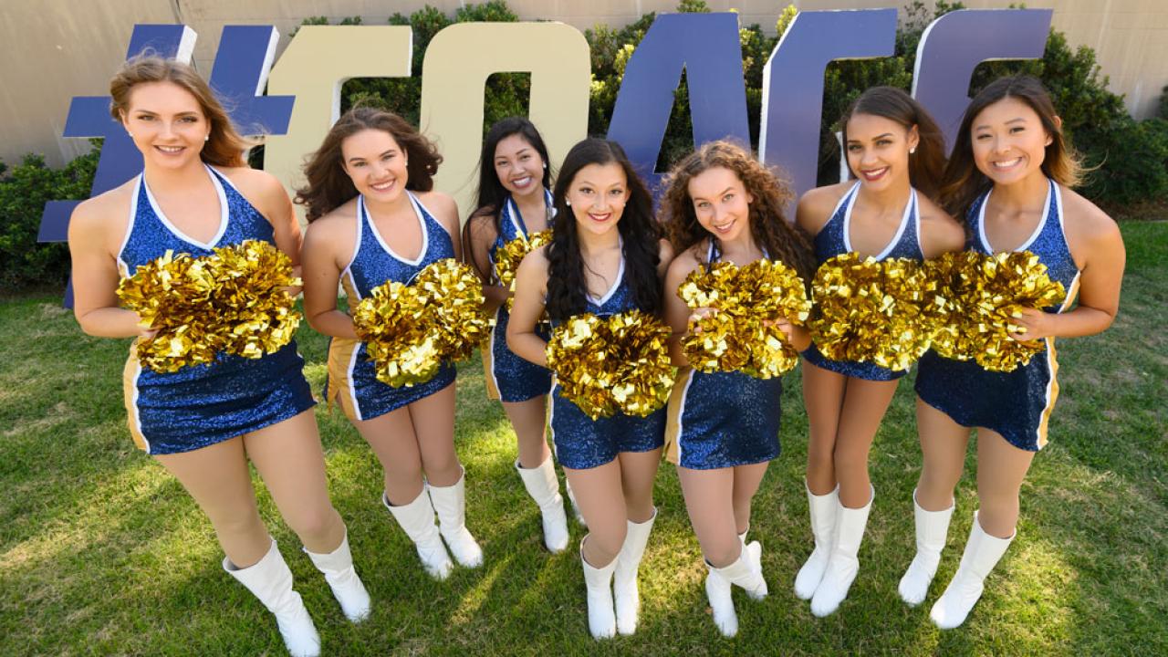 Seven members of the Dance Team in front of #GoAgs sign